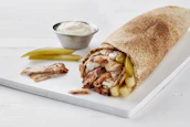 A close-up of a juicy shawarma wrap being held, steam rising invitingly.
