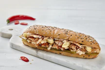 a sandwich with meat, cheese, and peppers on a cutting board