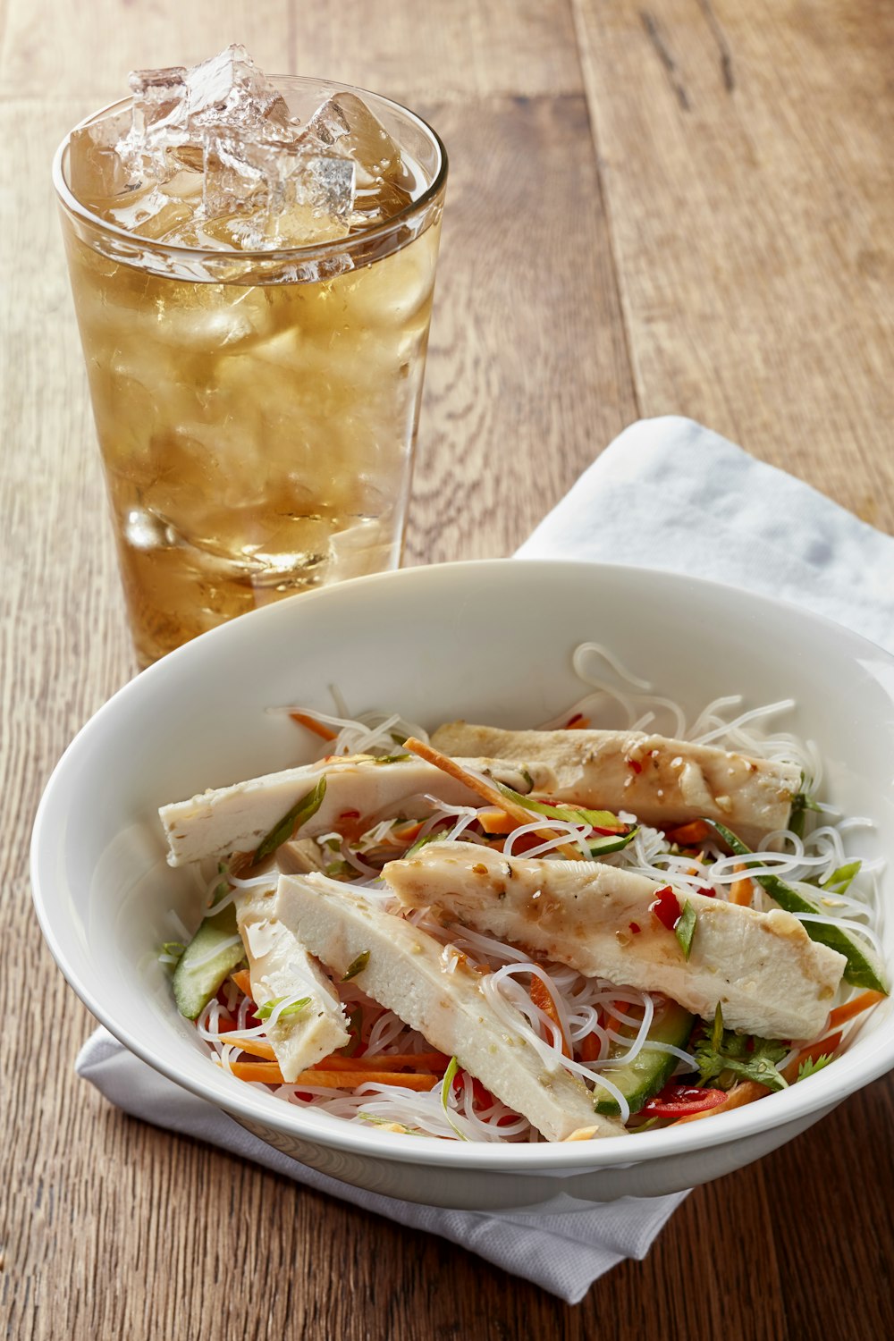 a white bowl filled with salad next to a glass of soda