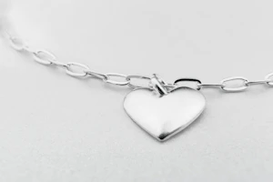 Elegant silver necklace with a minimalist pendant displayed on a black velvet background.