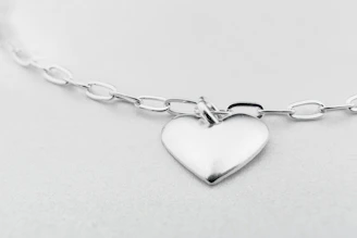 Elegant silver necklace with a subtle violet pendant, displayed on a minimalist white background.
