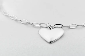 Soft-focus image of a silver-platinum pendant reflecting subtle charcoal grey tones