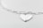 A heart-shaped silver pendant attached to a glossy chain with oval links, set against a soft, light gray background. The whole setup gives a minimalist and elegant impression.