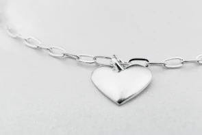Elegant silver necklace with a shimmering pendant displayed against a soft, neutral background.