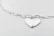 Minimalist wooden pendant hanging delicately on a thin chain against a soft background.