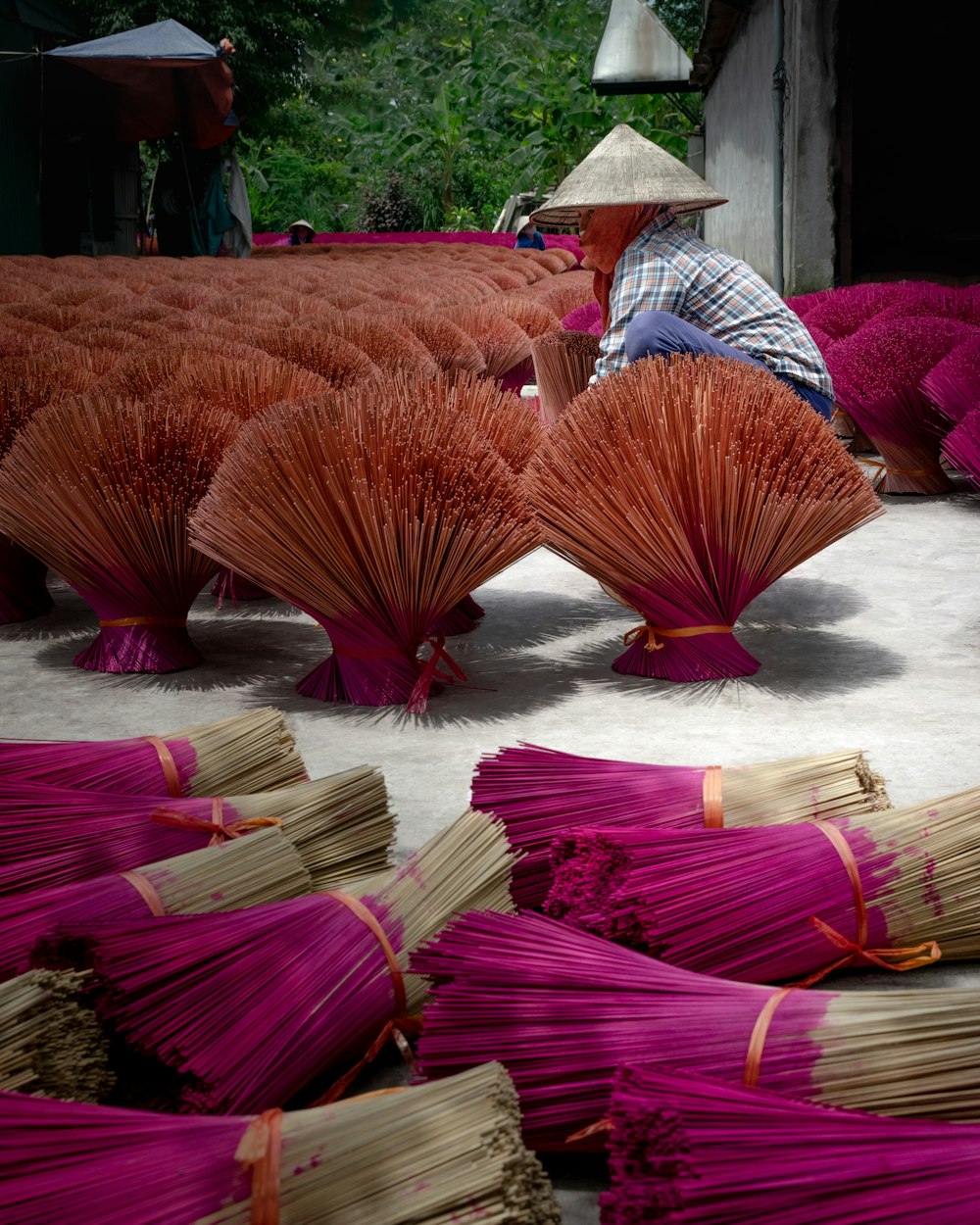 a man sitting on the ground next to a pile of purple umbrellas