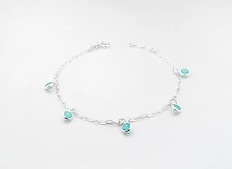 Delicate bracelets with turquoise and fuchsia accents resting on desert stones.
