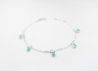 a silver bracelet with turquoise beads and charms