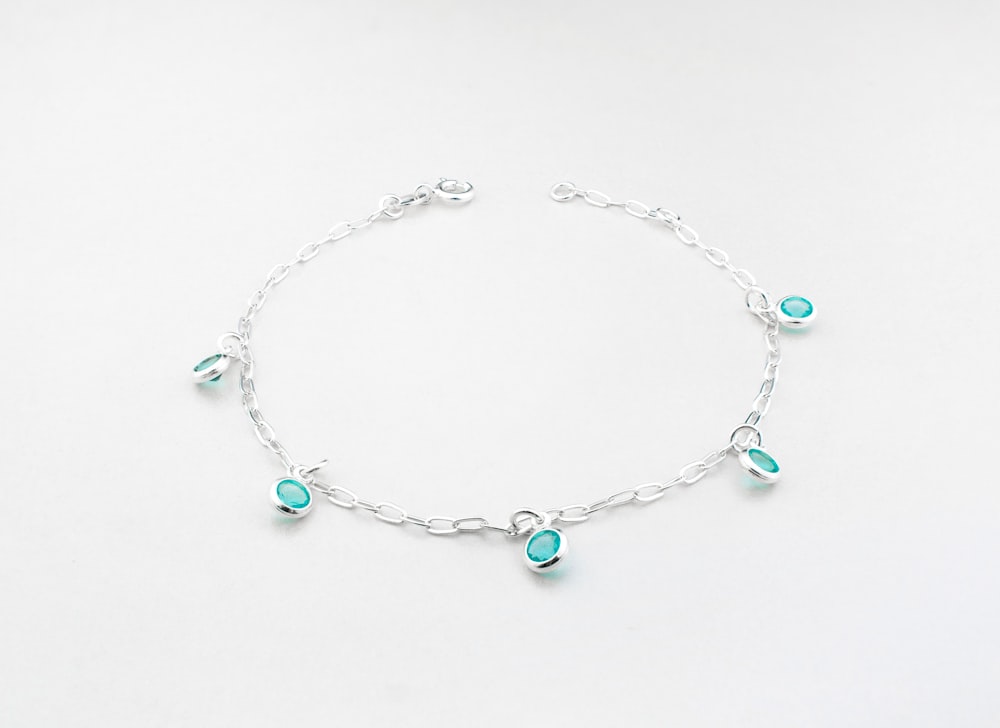 a silver bracelet with turquoise beads and charms