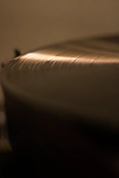 Close-up shot of a glowing orange vinyl record partially pulled from its rough, torn paper sleeve.