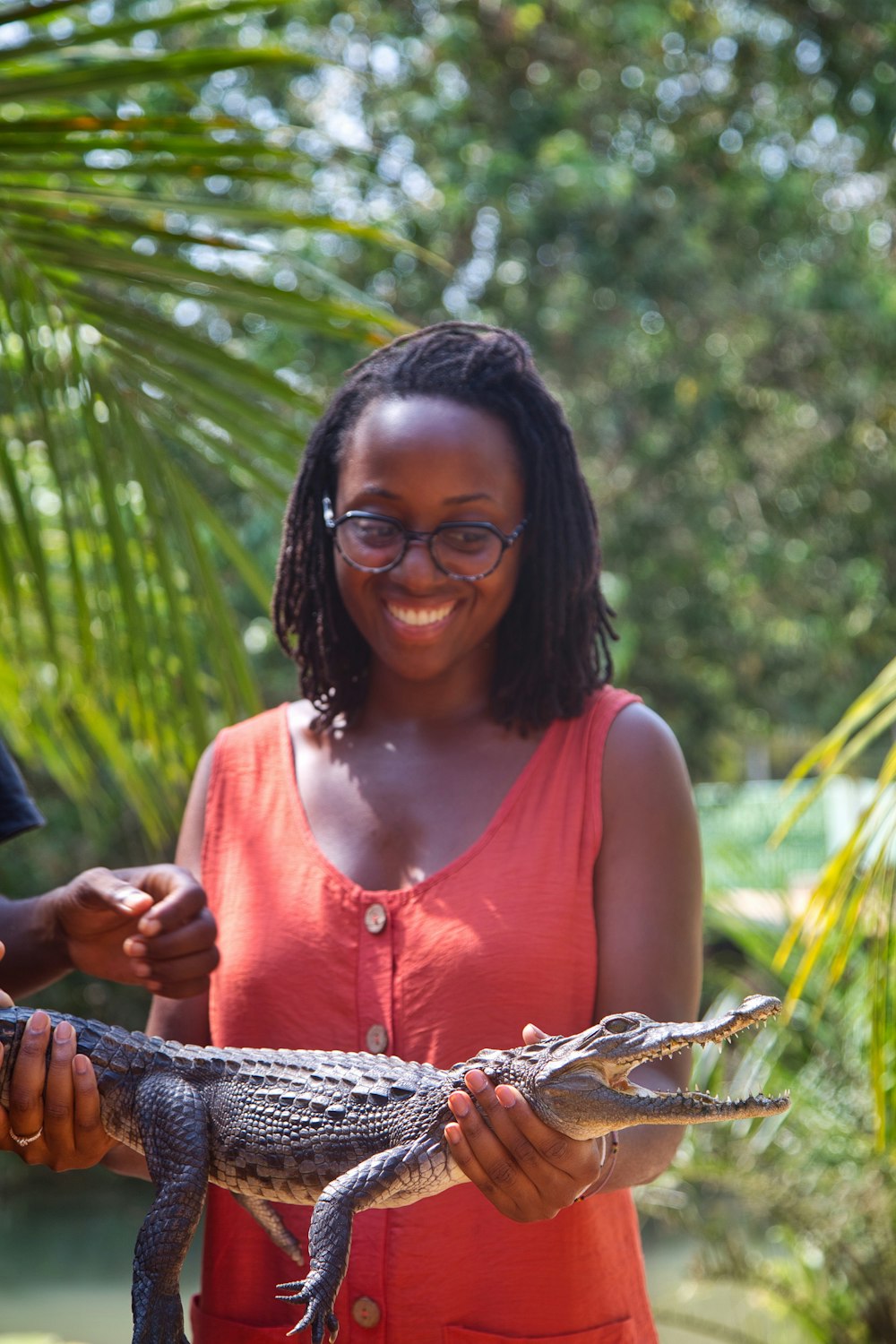 a woman holding a small alligator in her hand