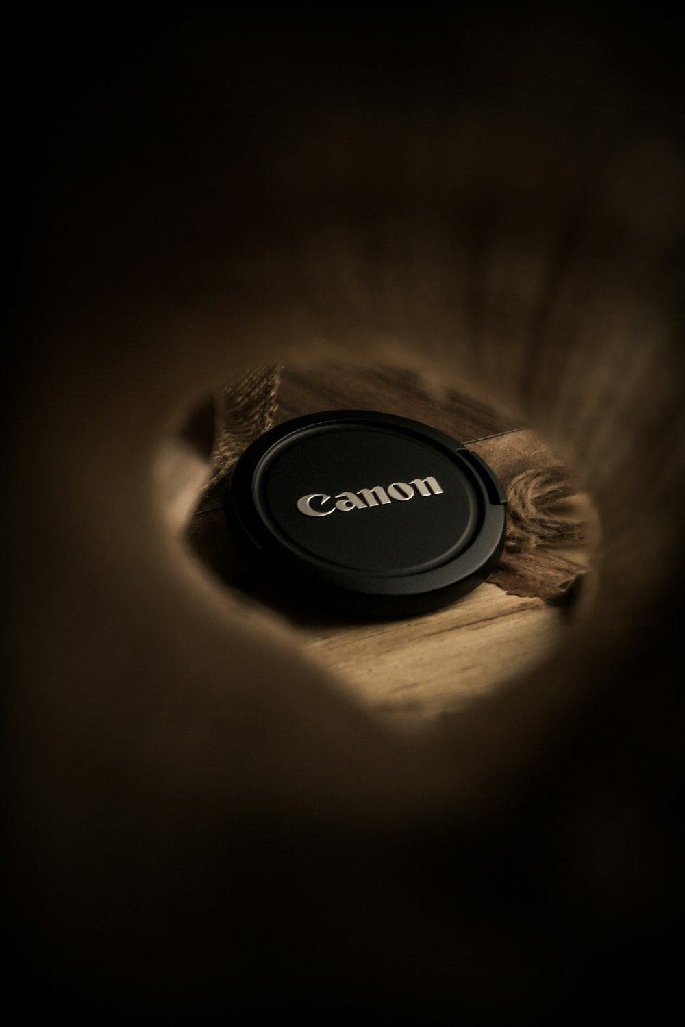 a camera lens cap sitting on top of a piece of wood