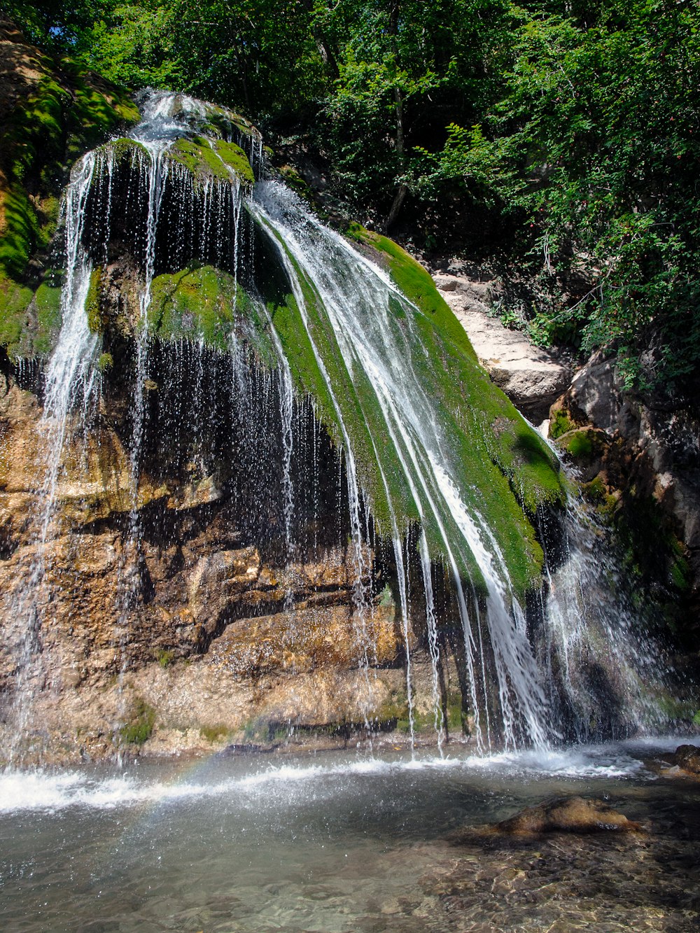 a small waterfall with green moss growing on it