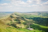 A panoramic view of scattered houses nestled among rolling green hills and winding paths.