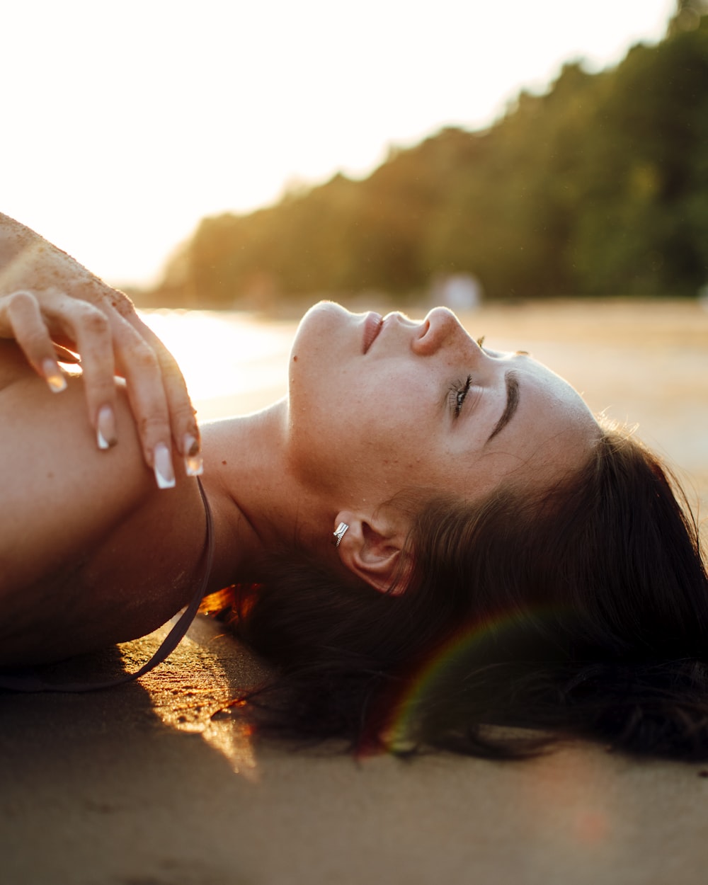 a woman laying on the beach with her eyes closed