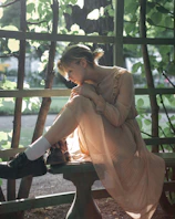 A serene outdoor scene of a person sitting quietly on a wooden bench amidst trees, reflecting.