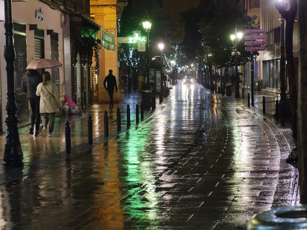 a city street at night with people holding umbrellas