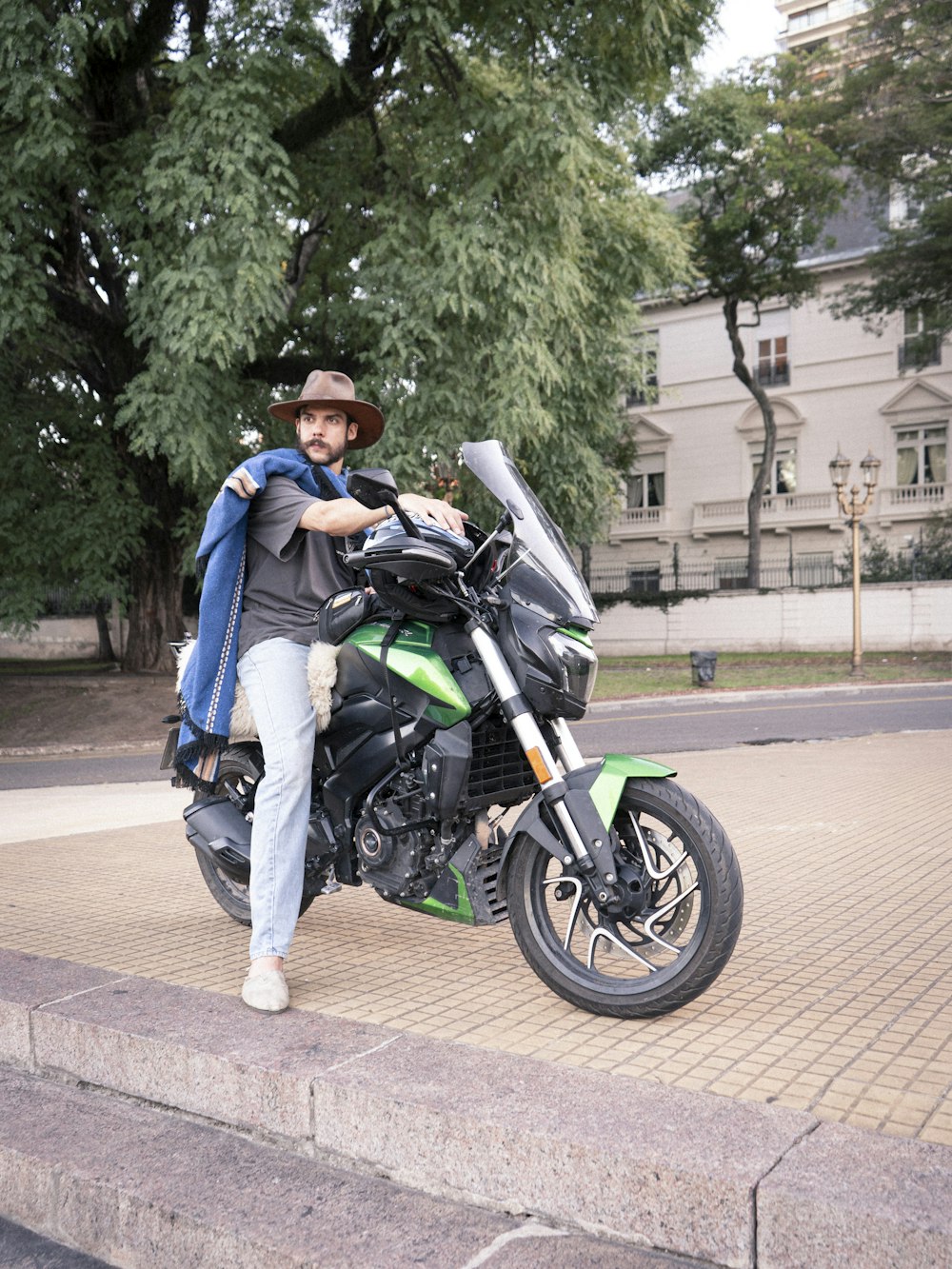 a man sitting on a motorcycle on a sidewalk