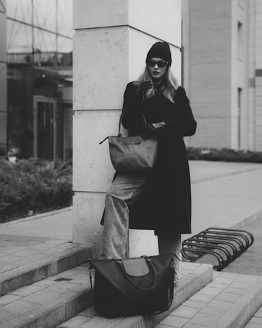 a woman leaning against a pillar with a bag