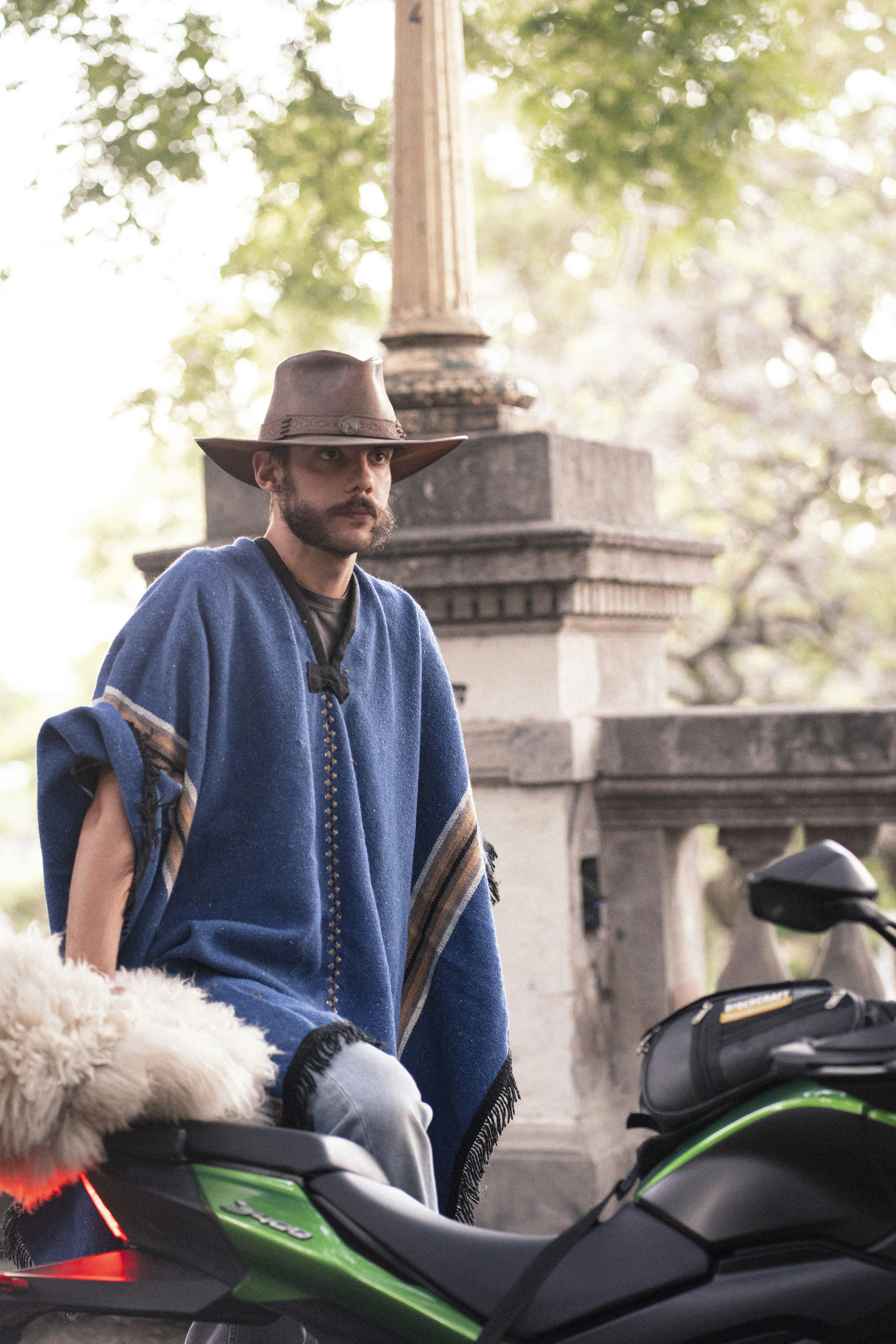 a man sitting on a motorcycle with a hat on