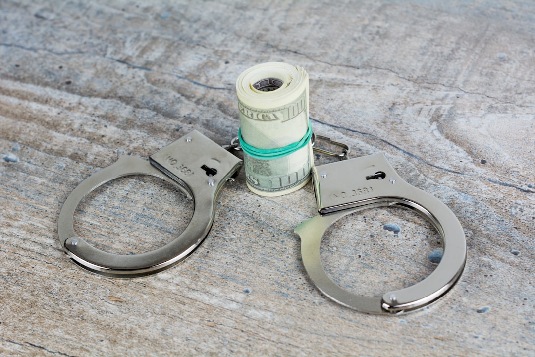 a pair of scissors and a roll of money on a table, Handcuffs and usa dollar banknotes on wooden background. Subscribe my