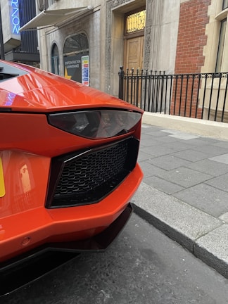 Wide shot of a vehicle wrapped with bold black and orange graphics parked on a city street.