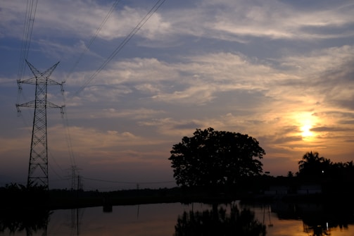 A high-voltage energy transmission tower under a sunset sky.