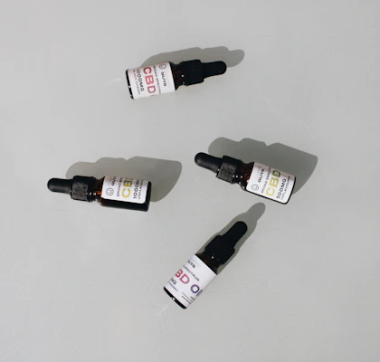 Bottles of cannabis oils and tinctures lined up with labels visible, set against a clean white backdrop.