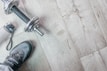 A pair of athletic shoes is next to a silver dumbbell on a light wooden floor. A water bottle with a carrying strap lies nearby.