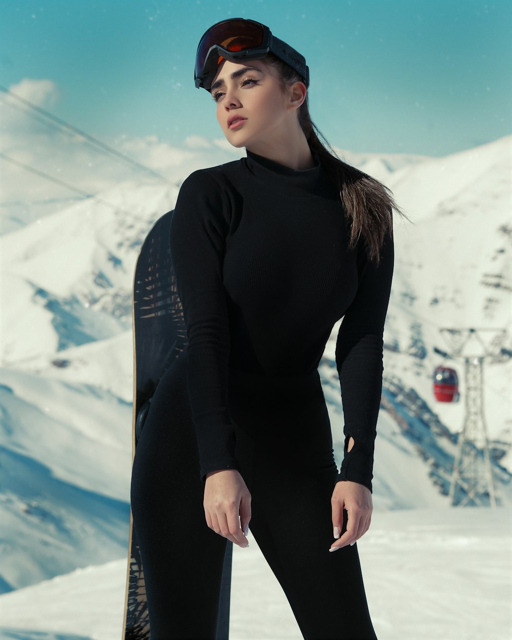 a woman in a black bodysuit holding a snowboard