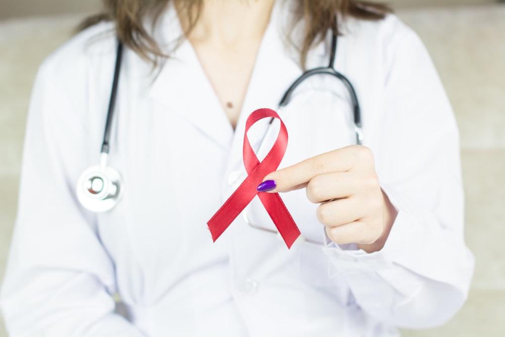 a woman in a white shirt holding a red ribbon