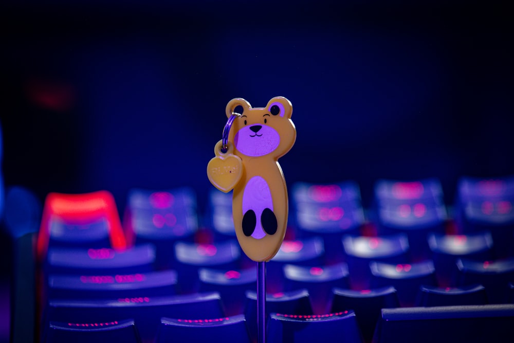 a teddy bear on a stick in front of a row of seats