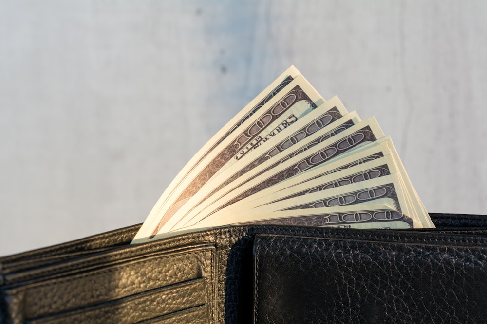 a wallet with a stack of twenty dollar bills sticking out of it