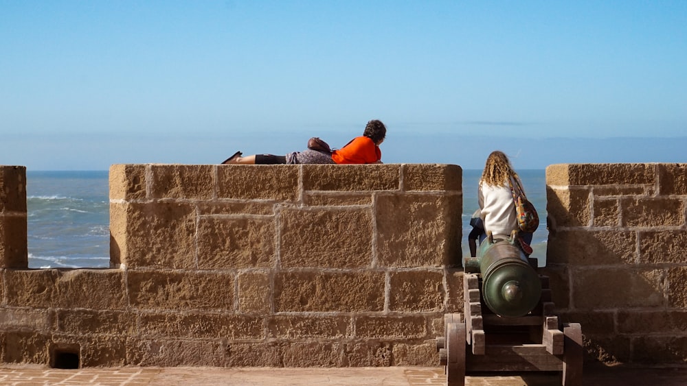 a couple of people sitting on top of a stone wall