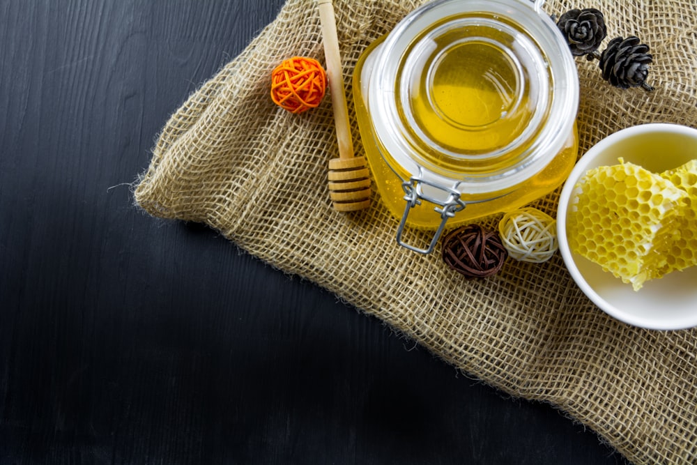 a jar of honey sits next to a bowl of honey