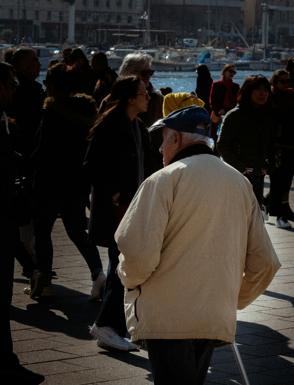 a group of people walking down a sidewalk next to a body of water