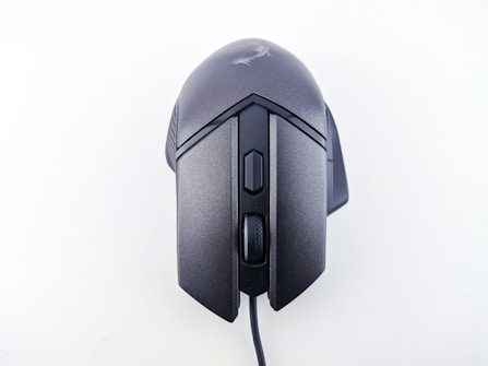 A wired computer mouse with a sleek, ergonomic design and matte black finish. It features a scroll wheel and additional buttons on the top, suitable for gaming or professional use.