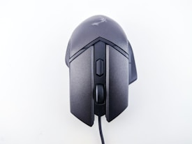 A wired computer mouse with a sleek, ergonomic design and matte black finish. It features a scroll wheel and additional buttons on the top, suitable for gaming or professional use.