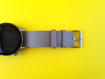 A bright circular icon showing a stylish wristwatch with a yellow strap