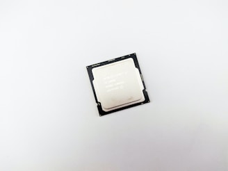 A central processing unit (CPU) placed on a plain white surface. The processor is mainly silver with a black border, displaying technical details.
