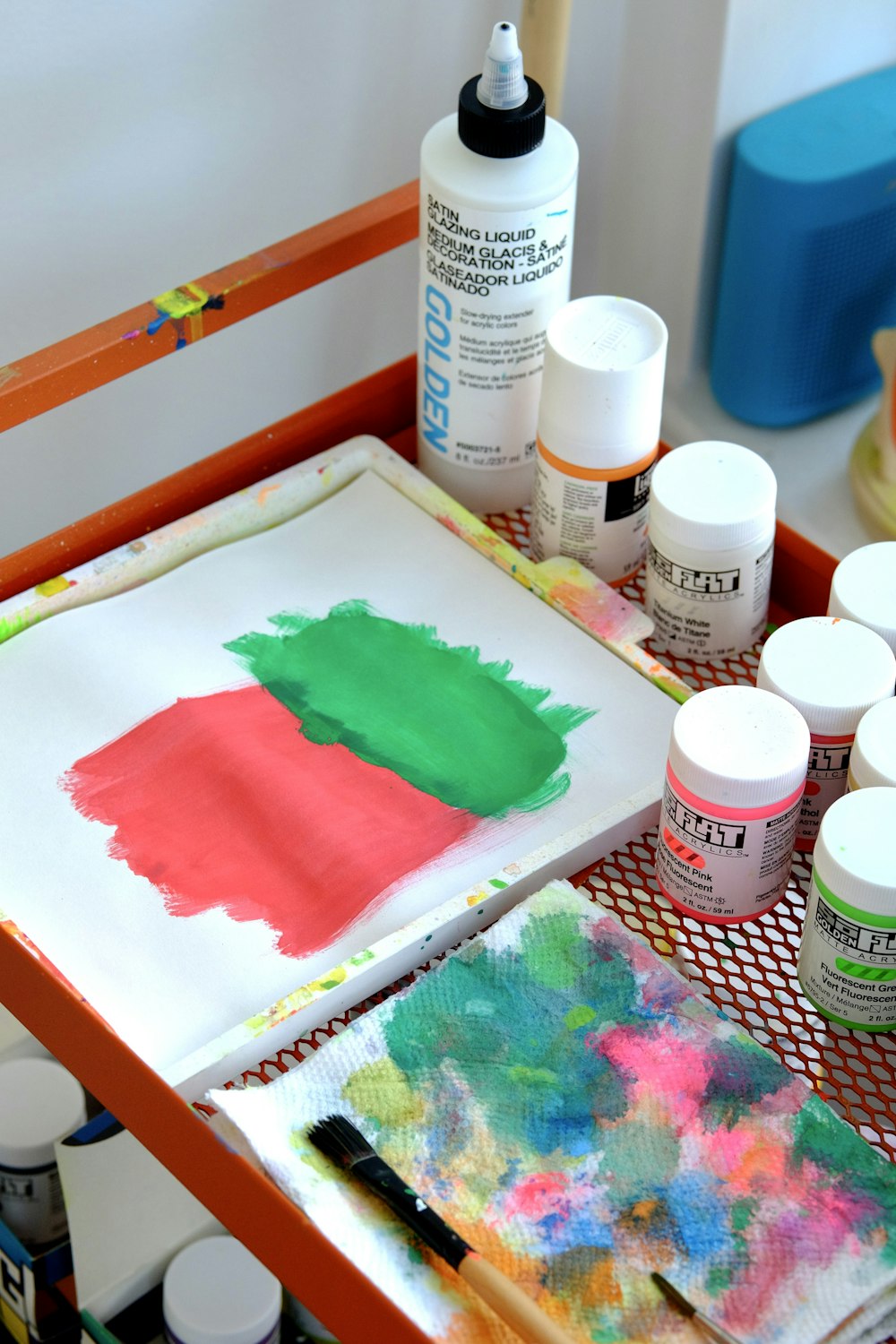 a table with paint, a brush, and a painting on it