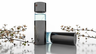A sleek, modern perfume bottle with a transparent section showing light blue liquid, surrounded by delicate flowering branches. The design is minimalistic and elegant, suggesting luxury and sophistication.