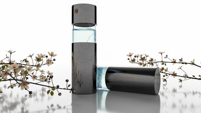 A sleek, modern perfume bottle with a transparent section showing light blue liquid, surrounded by delicate flowering branches. The design is minimalistic and elegant, suggesting luxury and sophistication.