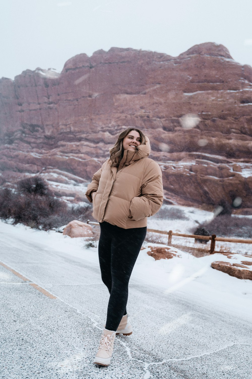 a woman walking down a road in the snow