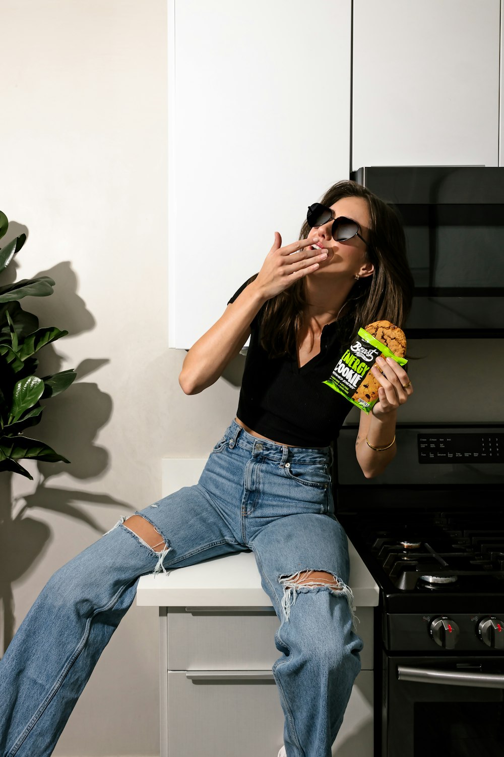Eine Frau sitzt auf einem Tresen und isst ein Sandwich