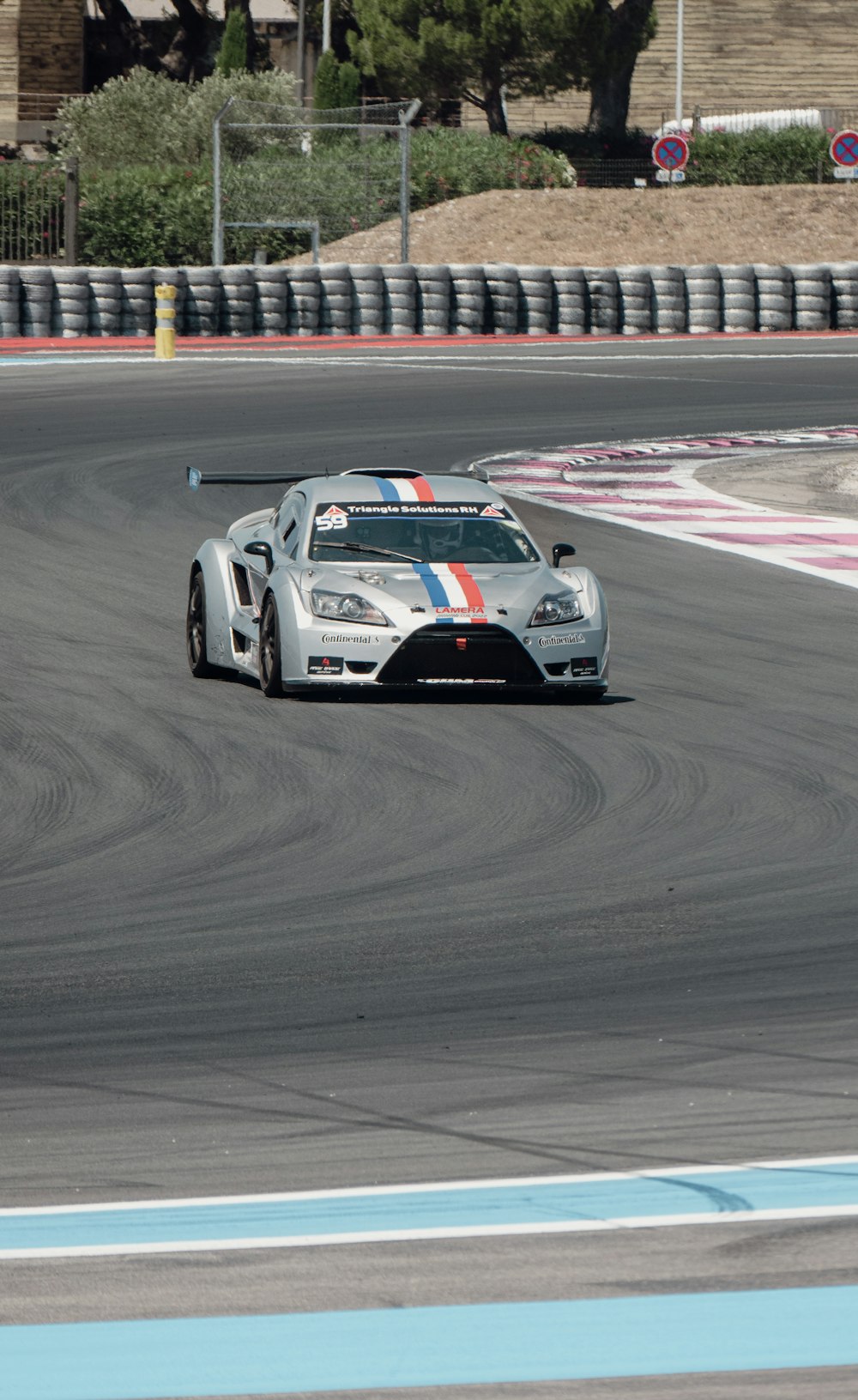 a silver sports car driving on a race track