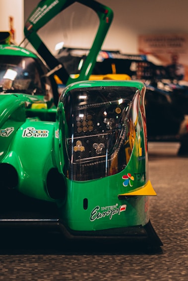 Close-up of a high-performance racing car refueling with a green-tinted biofuel at a track pit stop.