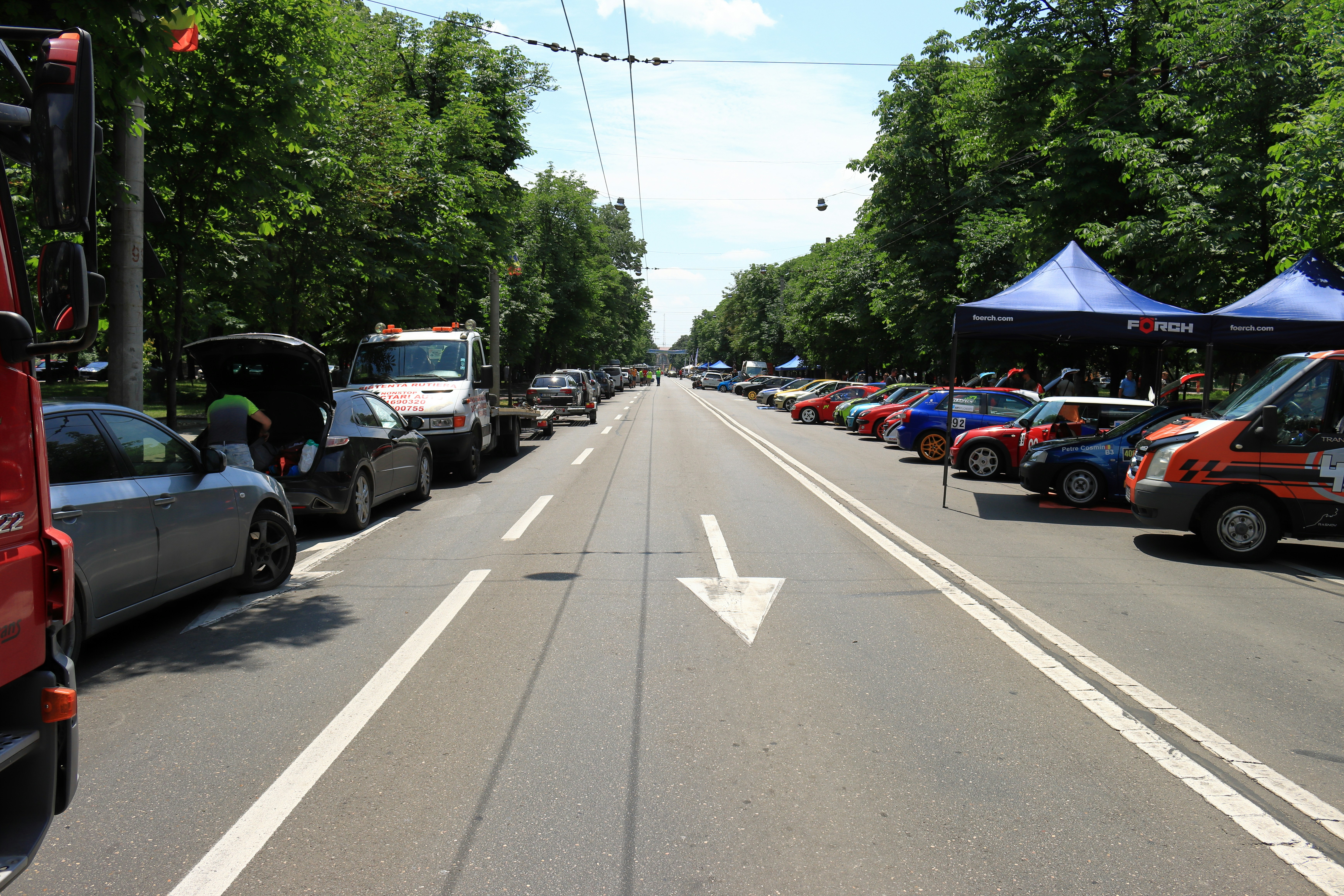 a street filled with lots of parked cars next to trees