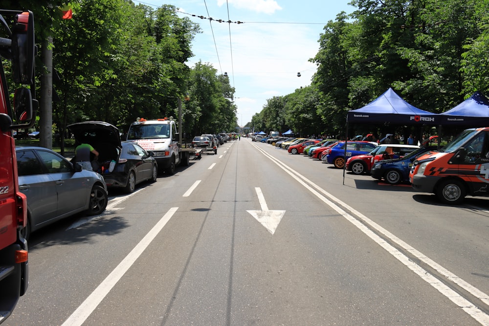 a street filled with lots of parked cars next to trees