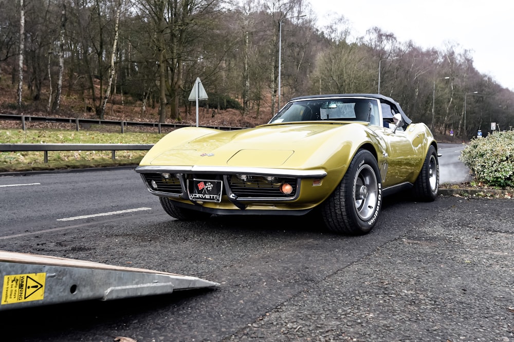 a yellow sports car is parked on the side of the road